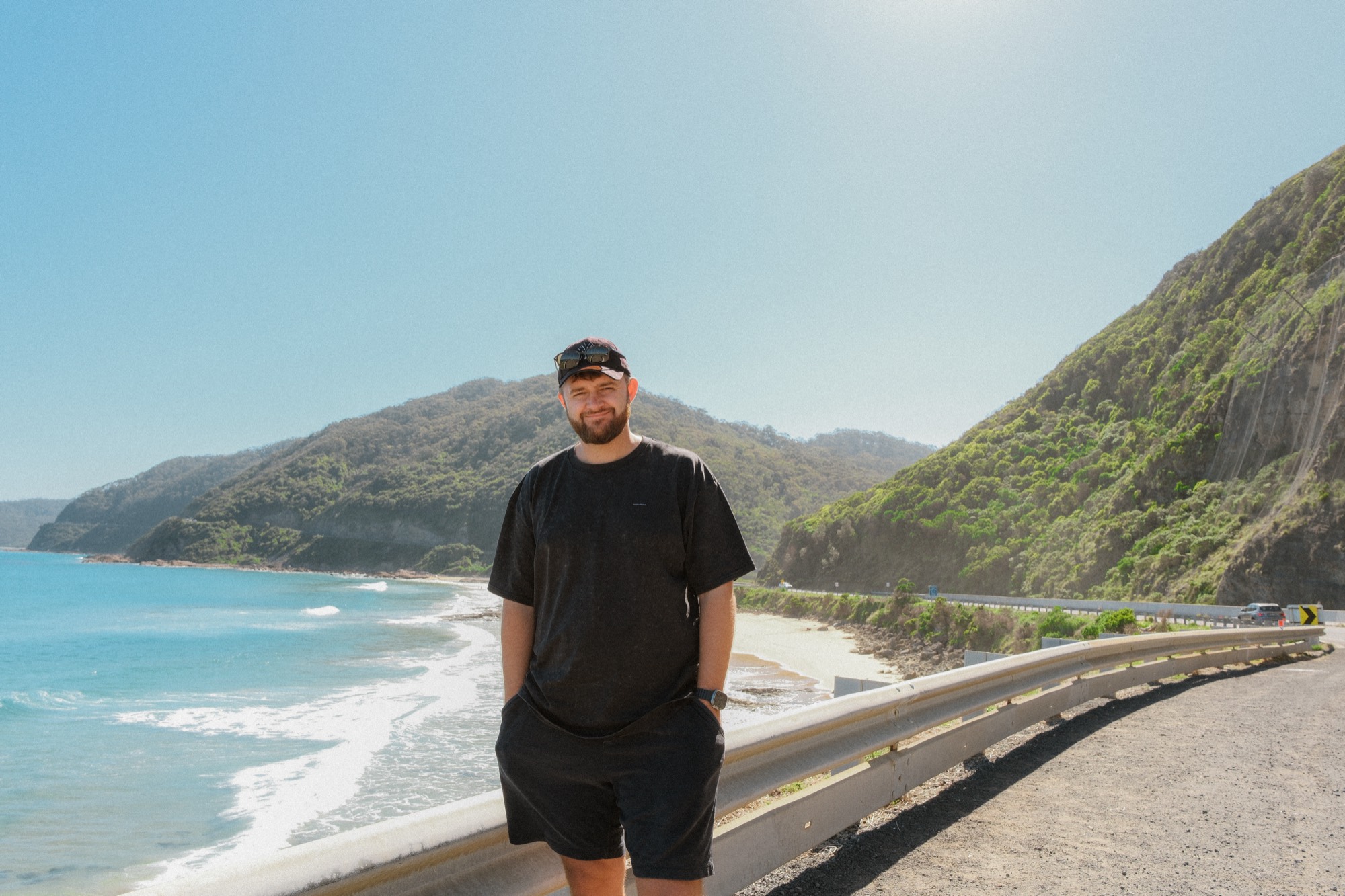 Igor Zdanevich standing by a coastal road, with the ocean and green hills behind him